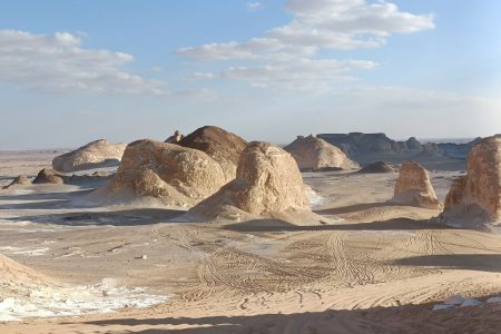 Unique, mushroom-shaped or anthropomorphic chalk-white rock formations scattered across the vast expanse of the White Desert in Bahariya Oasis under a clear blue sky