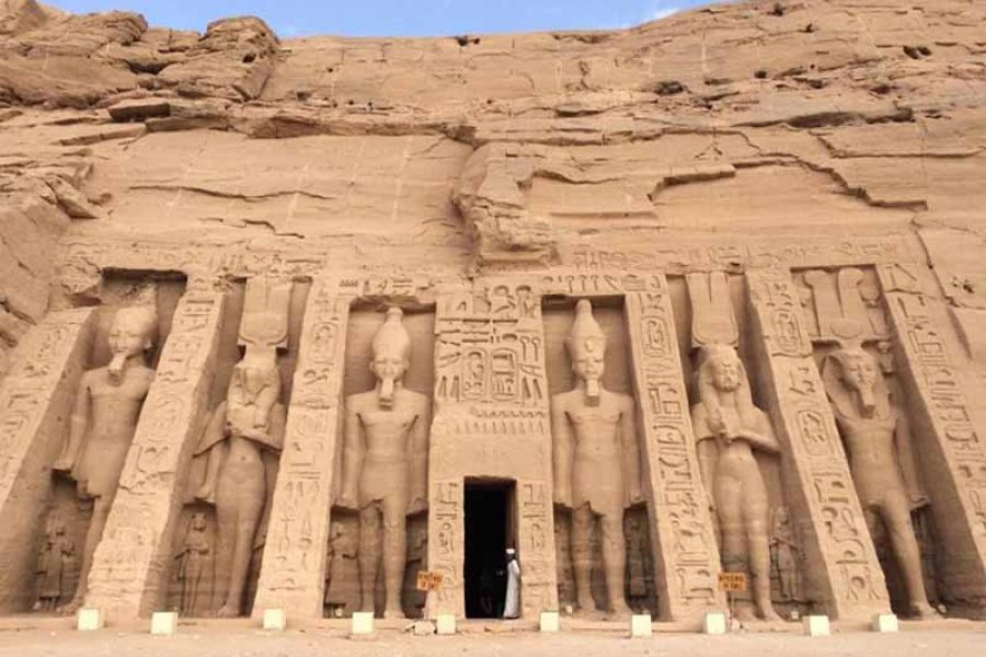 The colossal facade of the Great Temple of Ramesses II at Abu Simbel, carved into a sandstone cliff, with four massive seated statues of the pharaoh guarding the entrance