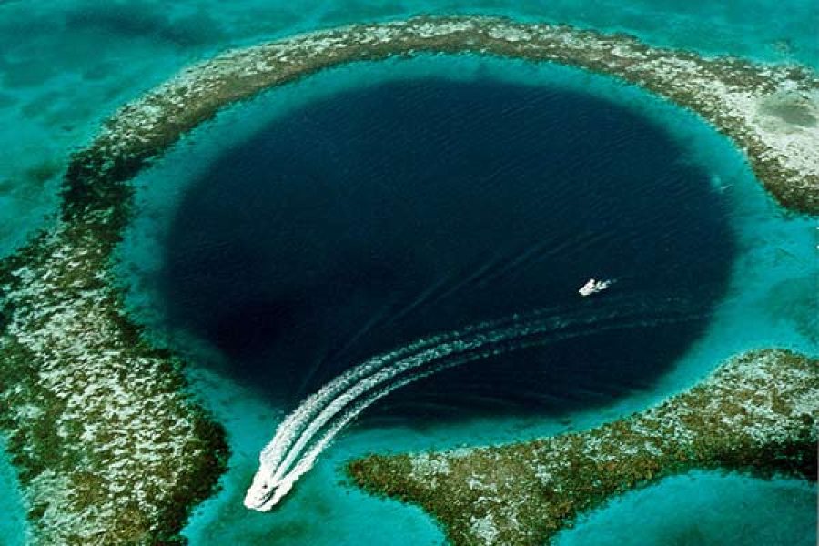deep blue sinkhole known as the Blue Hole in Dahab, Egypt, seen from above, contrasting sharply with the lighter turquoise of the surrounding Red Sea waters and coral reef