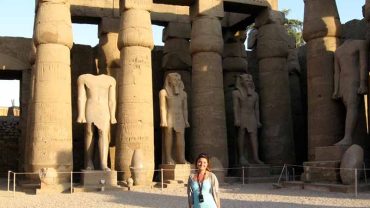 A client standing amidst the towering papyrus-bundle columns of Luxor Temple, conveying the immense scale and architectural beauty of the ancient Egyptian monument