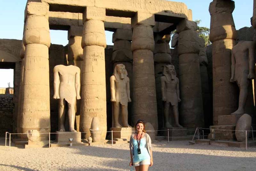 A client standing amidst the towering papyrus-bundle columns of Luxor Temple, conveying the immense scale and architectural beauty of the ancient Egyptian monument