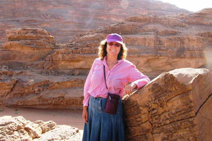 A client smiling broadly and posing happily amidst the stunning red sand dunes and unique rock formations of Wadi Rum, conveying pure joy in the desert landscape