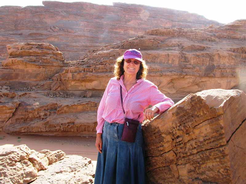 A client smiling broadly and posing happily amidst the stunning red sand dunes and unique rock formations of Wadi Rum, conveying pure joy in the desert landscape